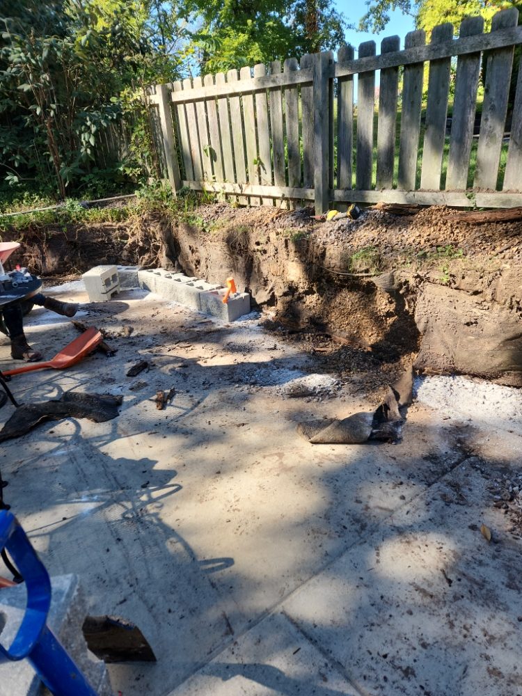 Eroded backyard slope before pool deck retaining wall project